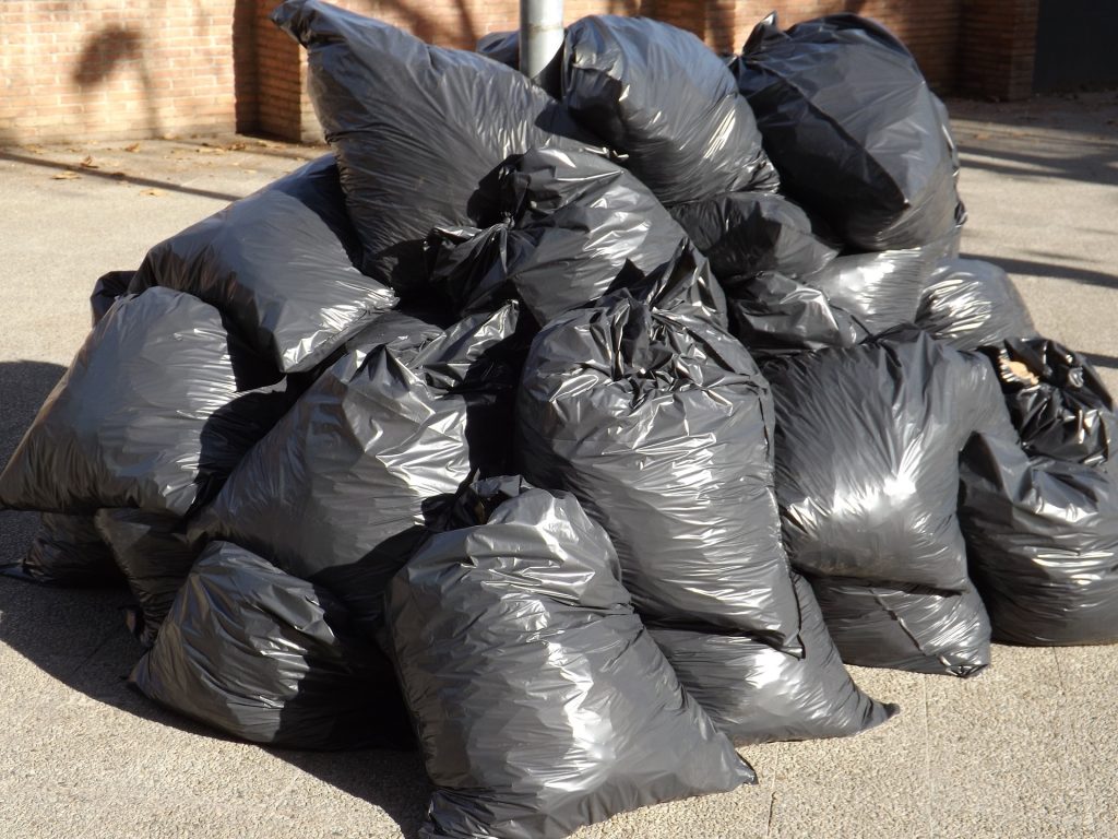 A pile of black bags sitting on the side of a road