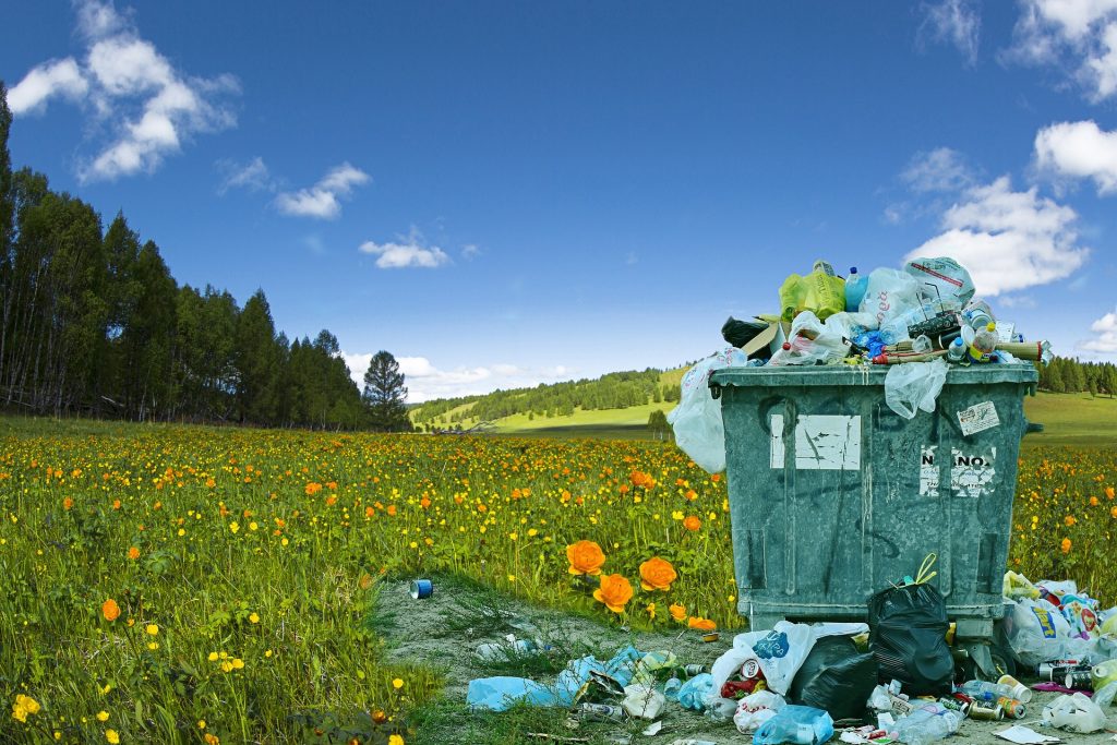 A rubbish can in a field full of flowers