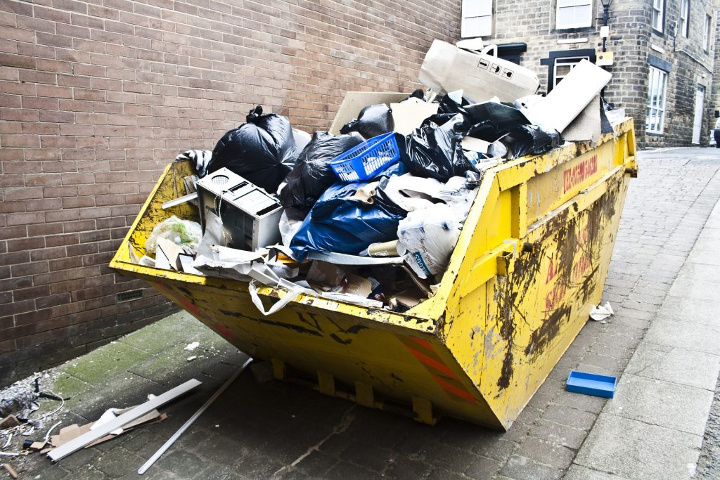 A skip filled with rubbish on the side of a street