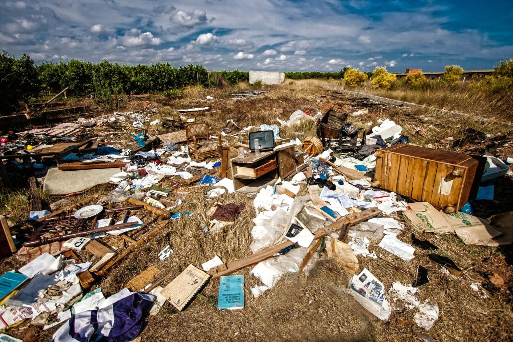 Household waste and furniture dumped in an open field, highlighting the need for cleanup and proper disposal services.